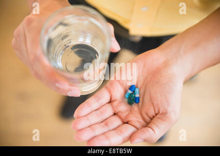 Close up of mixed race man holding medicine and glass of water Stock Photo