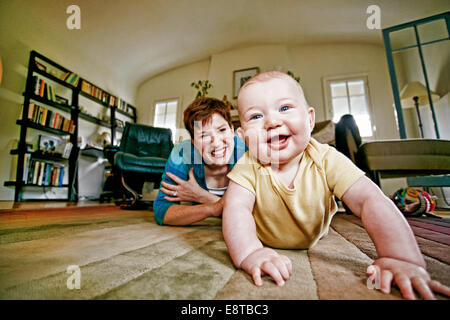 Caucasian mother and baby playing on living room floor Stock Photo