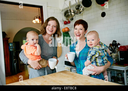 Caucasian mothers holding babies in kitchen Stock Photo