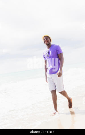 Mixed race man walking on beach Stock Photo