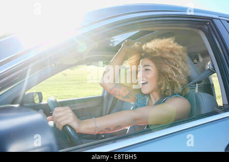 Hispanic woman cheering and driving car
