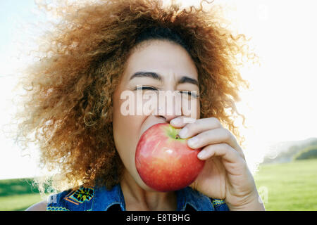 Hispanic woman eating apple outdoors Stock Photo