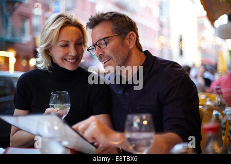 Caucasian couple reading menu at urban cafe, New York City, New York, United States Stock Photo