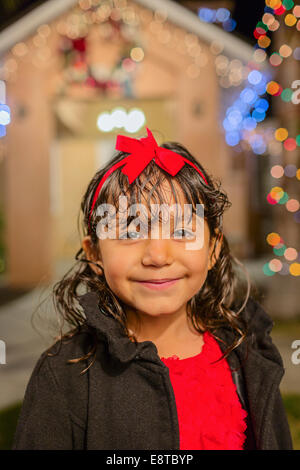 Hispanic girl smiling outside house decorated with string lights Stock Photo
