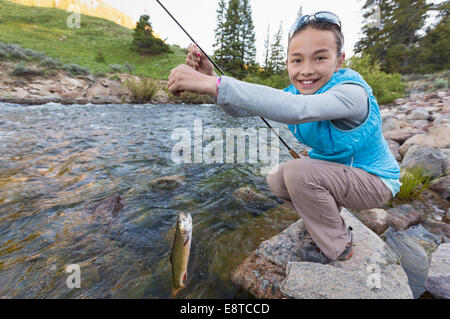 Mixed race girl fishing in river Stock Photo