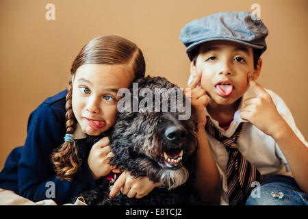 Mixed race children making faces with dog Stock Photo