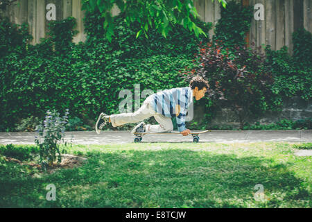 Mixed race boy riding skateboard on sidewalk Stock Photo
