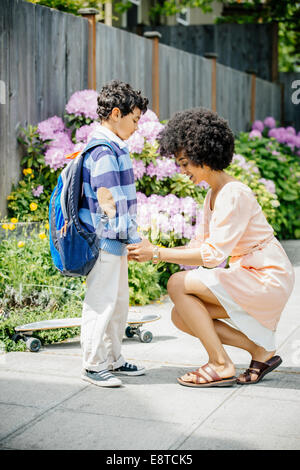 Mixed race mother holding sons hands on suburban sidewalk Stock Photo