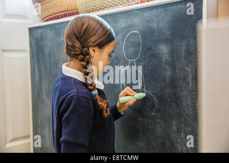 Mixed race girl drawing on chalkboard Stock Photo