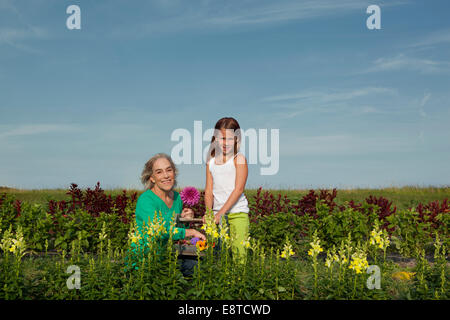 Caucasian grandmother and granddaughter picking flowers on farm Stock Photo