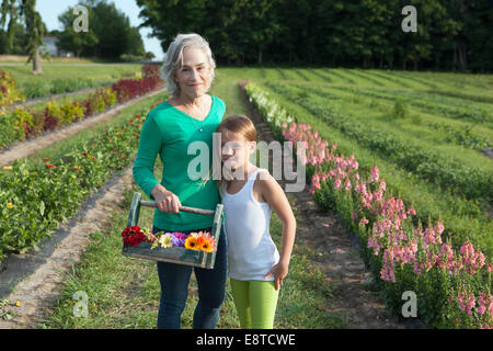 Caucasian grandmother and granddaughter picking flowers on farm Stock Photo