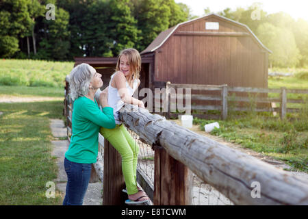Caucasian grandmother and granddaughter smiling at farm fence Stock Photo