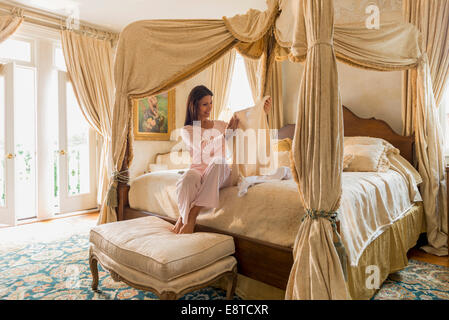 Hispanic woman admiring clothes on bed Stock Photo