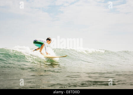 Mixed race boy surfing in waves Stock Photo