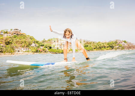 Mixed race girl surfing in waves Stock Photo