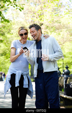 Caucasian couple using cell phone in park Stock Photo