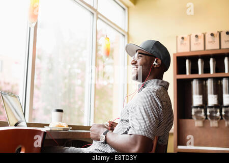 Laughing Black man using laptop in coffee shop Stock Photo