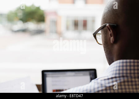 Black man using laptop at window Stock Photo