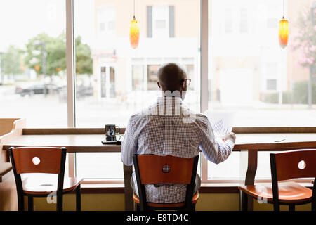 Black man reading paperwork in coffee shop Stock Photo