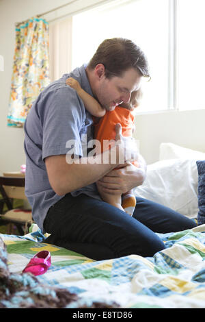 Caucasian father holding daughter on bed Stock Photo