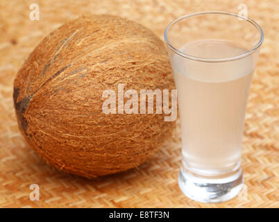 Fresh Coconut with water in a glass on textured surface Stock Photo