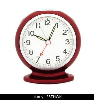 Red mechanical alarm clock with luminous hands after 10 am in a morning with alarm set at time 7 am to illustrate being late concept Stock Photo