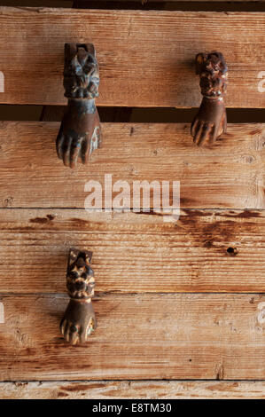 Home vintage decorations: detail of a wooden door with one door knocker in the shape of hand Stock Photo