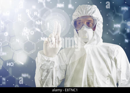 Chemist in protective clothing is pressing button of virtual touch screen. Stock Photo
