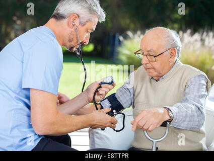 Doctor Measuring Blood Pressure Of Senior Man Stock Photo