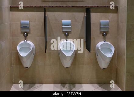 Set of urinals in a modern male toilet facility, with tiled floor and wall Stock Photo