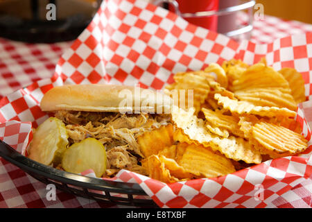 A pulled pork sandwich with potato chips and pickles Stock Photo