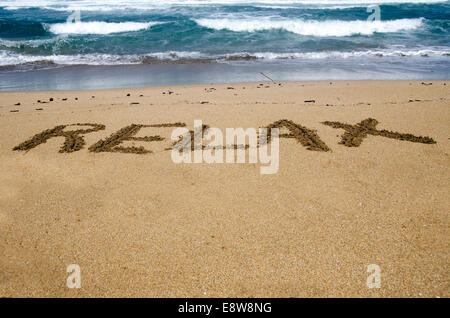 The word relax written in the sand on a beach Stock Photo