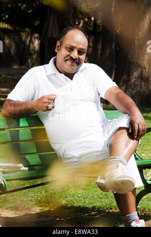 1 Indian Man Sitting in Park and Drinking Tea Stock Photo