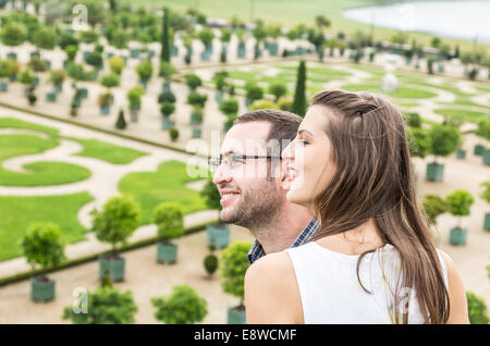 Profile of a young happy couple enjoying a beautiful French garden during a beautiful day. The focus is selective on the woman. Stock Photo