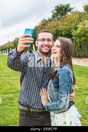 Young happy couple taking a selfie in a beautiful French garden. Stock Photo