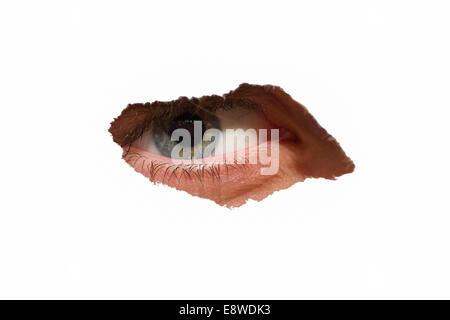 Female eye looking at you through the hole in white surface. Abstract image Stock Photo