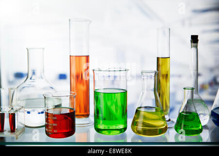 Beakers of various solutions on shelf in lab Stock Photo