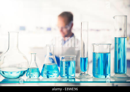 Close up of various solutions in beakers on shelf in lab Stock Photo