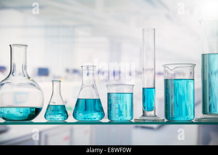 Beakers with solution on shelf in lab Stock Photo