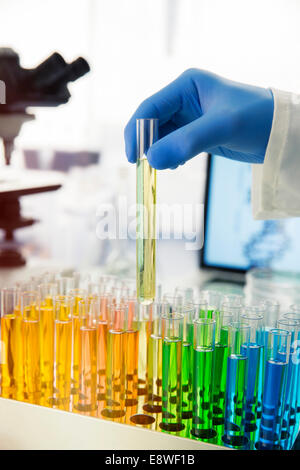 Scientist picking test tube out of rack on counter in lab Stock Photo