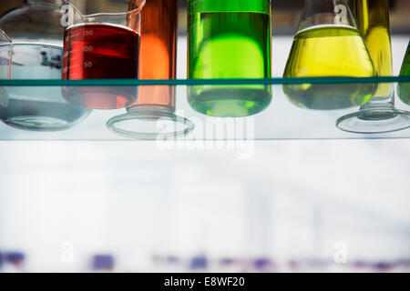 Close up of beakers with solution on shelf in lab Stock Photo