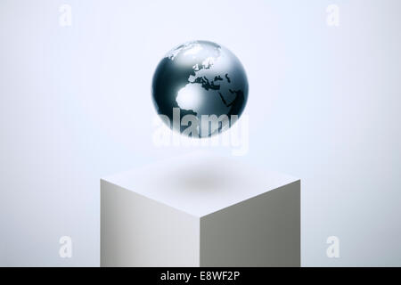 Globe hovering over pedestal Stock Photo