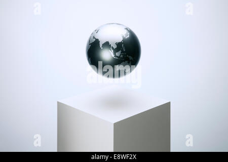 Globe hovering over pedestal Stock Photo