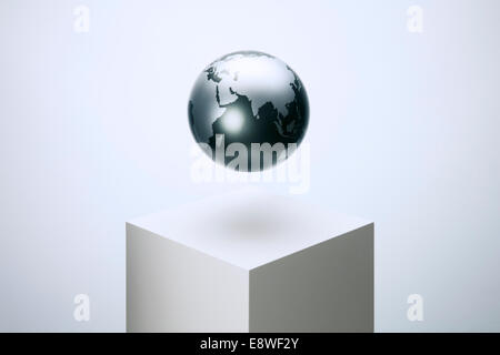 Globe hovering over pedestal Stock Photo