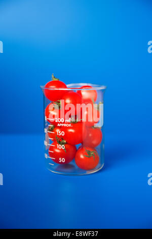 Beaker of small tomatoes on blue counter Stock Photo