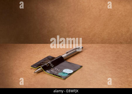 Credit card bent over pen on counter Stock Photo