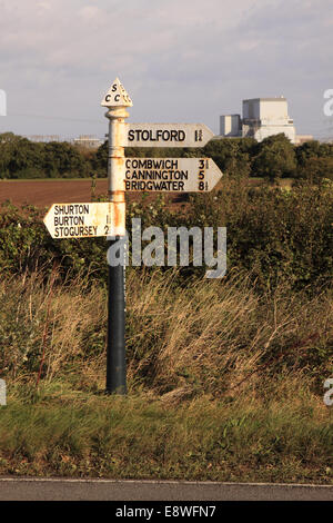 Hinkley Point nuclear power station in background with old road sign pointing to local villages Shurton Burton Stolford Stock Photo