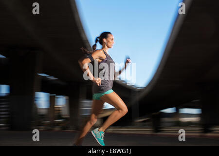 Woman running through city streets Stock Photo