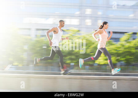 Couple running through city streets together Stock Photo