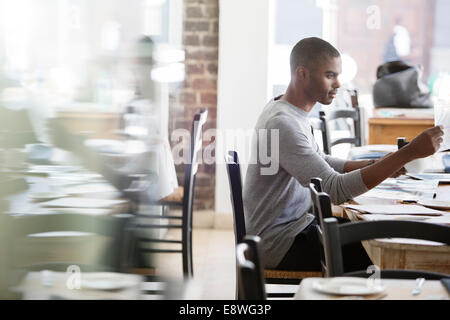 Businessman looking through documents in cafe Stock Photo